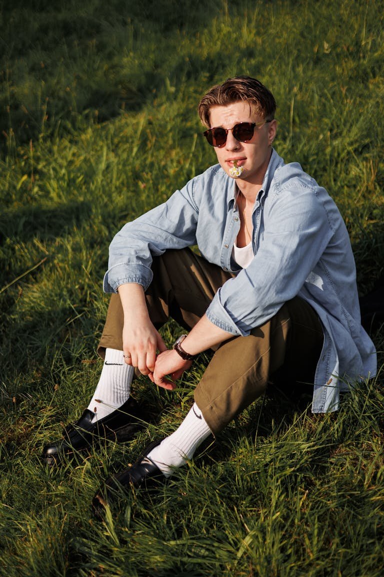 A man sitting in the grass wearing sunglasses